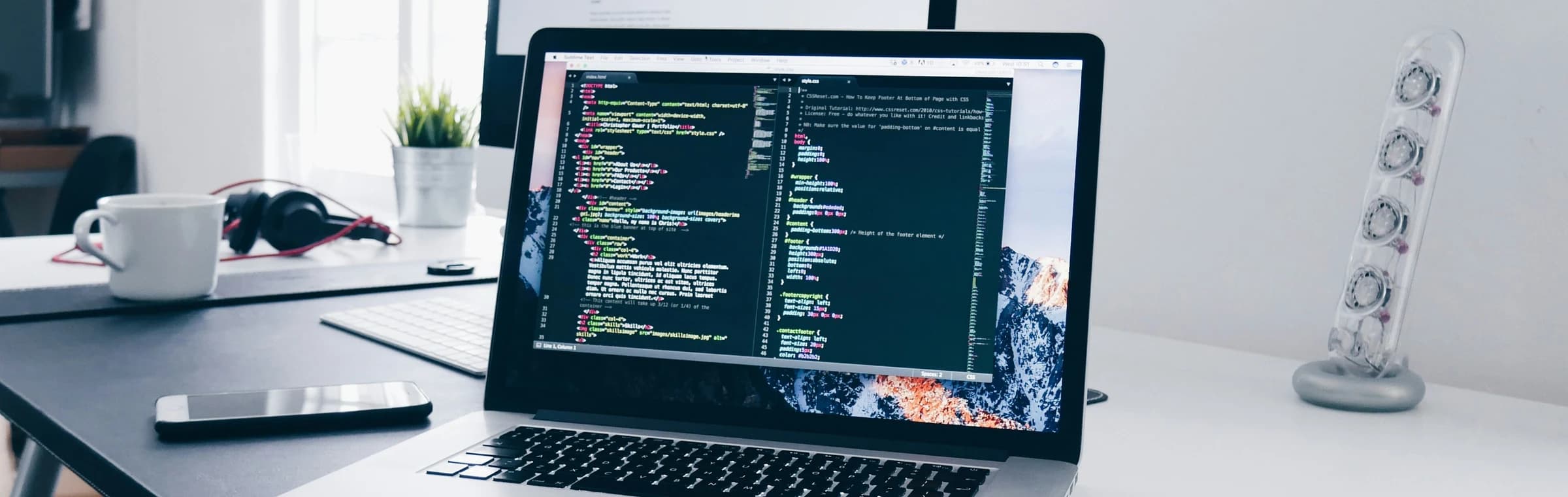 A laptop displaying source code on a bright workspace
